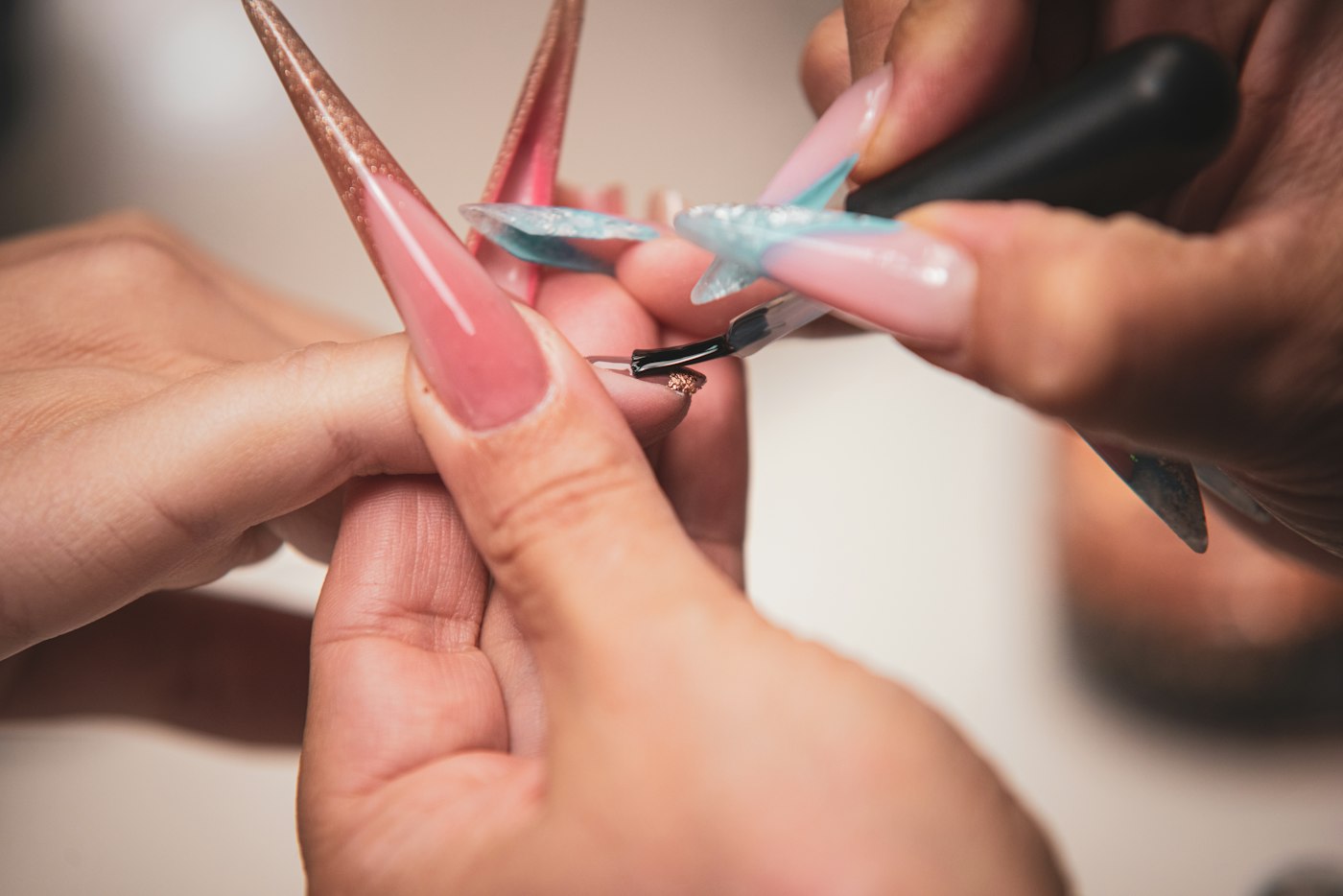 Technician sculpting long pink nail extensions